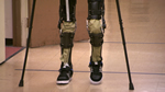 Photo showing a pair of legs aided by crutches and an exoskeleton